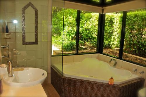 baño con bañera, lavabo y ventana en Waterfall Cottages, en Margaret River Town