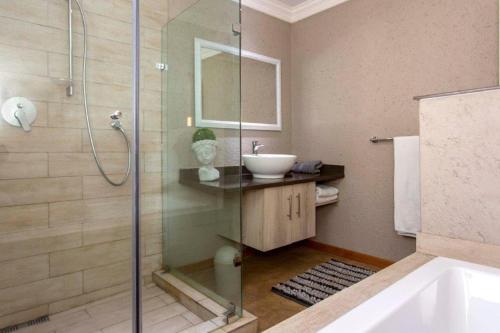 a bathroom with a shower and a sink and a tub at Ilanga Game & Fishing Lodge in Dullstroom