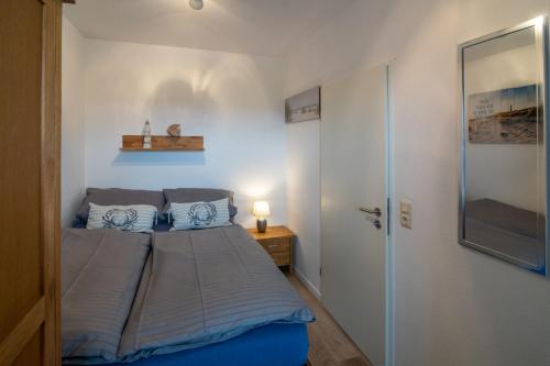 um pequeno quarto com uma cama e uma porta de vidro em Lüttje Nest em Dornumersiel