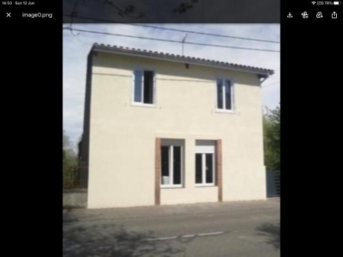 a small white house with black windows on a street at No 5 Plaisance Studio in Plaisance