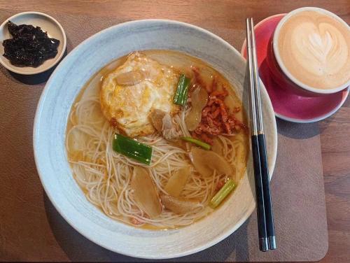a bowl of soup with noodles and a cup of coffee at Good Day Homestay in Nangan