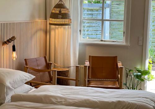 a bedroom with two chairs and a bed and a window at Hotel Blomme's Place in Snogebæk