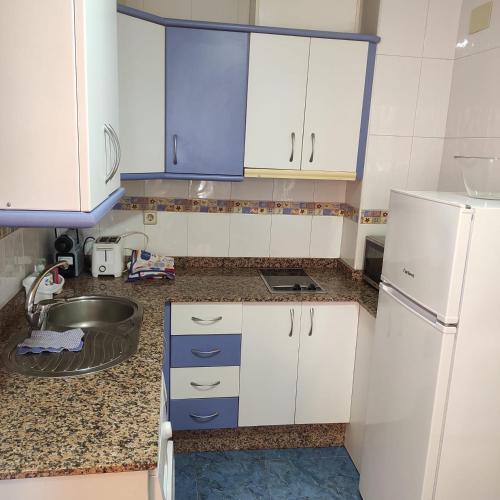 a kitchen with white cabinets and a sink at Apartamentos Azahar in Puente de Génave