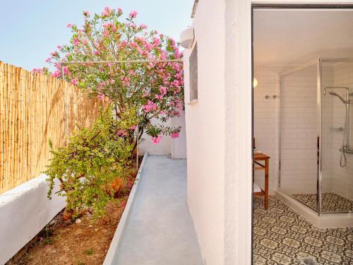 une passerelle menant à une salle de bains ornée de fleurs roses dans l'établissement Psathi Beach House, à Kimolos