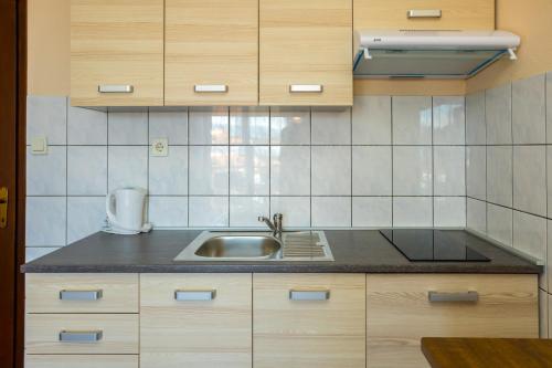a kitchen with wooden cabinets and a sink at Apartments Filosevic by El-Pi Tours in Njivice