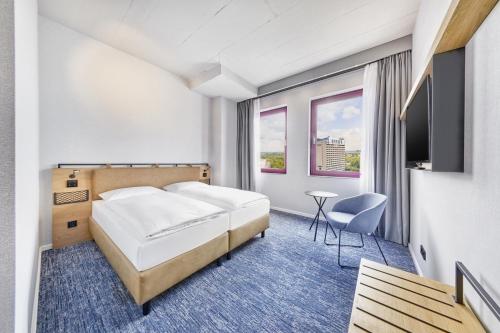 een hotelkamer met een bed en een televisie bij H2 Hotel Düsseldorf Seestern in Düsseldorf