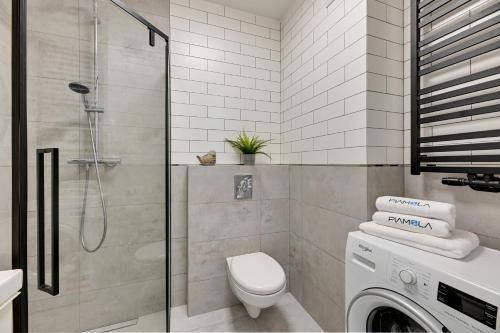 a bathroom with a shower and a washing machine at BURSZTYNOVA Apartamenty Piamola in Kąty Rybackie