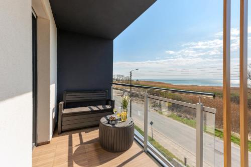 a balcony with a table and a view of the ocean at BURSZTYNOVA Apartamenty Piamola in Kąty Rybackie