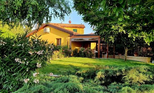 a yellow house with a yard with grass and trees at Osteria da Cesare e Locanda in Castel San Pietro Terme