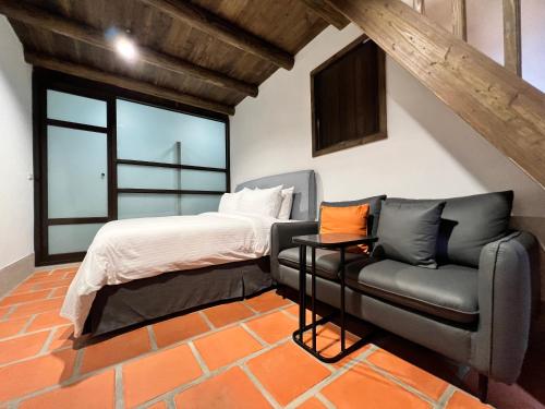 a bedroom with a bed and a couch and a chair at 金門 日玥居 古厝民宿 Sunmoon19 B&B in Jinning