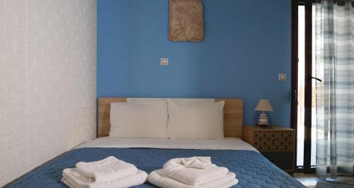 a bed with towels on it with a blue wall at Villa azzuro ground floor in Nea Kalikratia