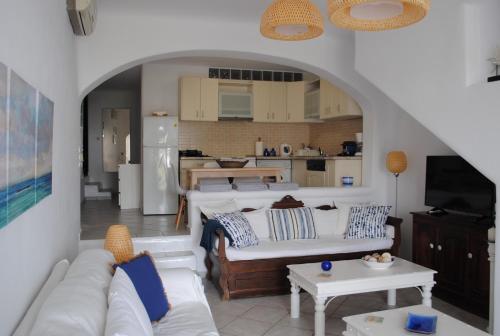a living room with a white couch and a kitchen at Sea and Sun beach house at Platis Gialos in Platis Gialos