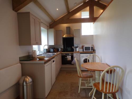 a kitchen with a table and a table and chairs at Detached barn with valley views near Cardigan in Cardigan