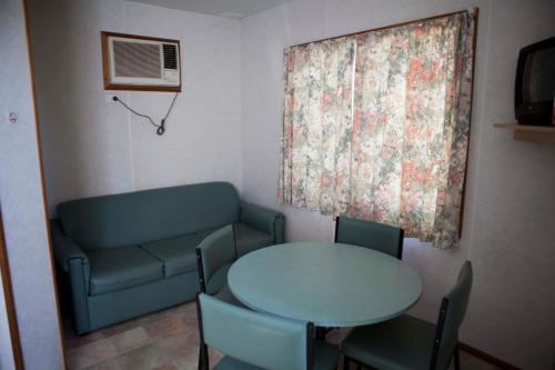 a room with a table and a couch and a table and chairs at Strayleaves Caravan Park in Shepparton