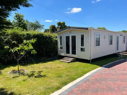 a white tiny house on a grassy yard at New Forest Hideaway- Self Catering Accommodation in Newbridge