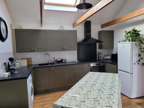 a kitchen with green cabinets and a white refrigerator at Beautiful barn with private log fired hot tub in Maidstone