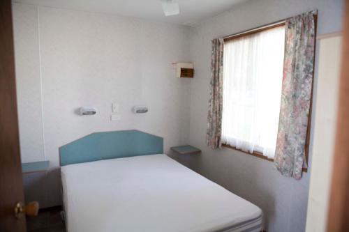 a small room with a bed and a window at Strayleaves Caravan Park in Shepparton