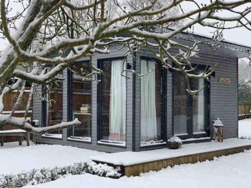 a house covered in snow with a tree at Self Contained Garden Studio with stunning views in Sissinghurst