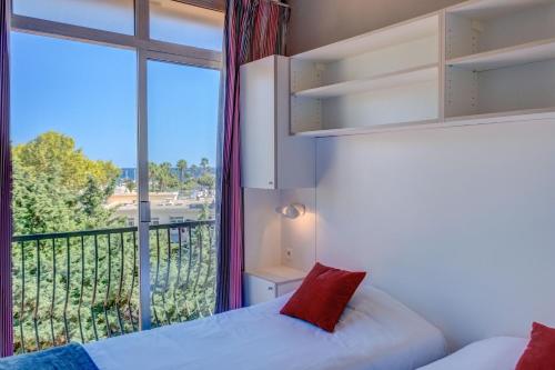 ein Schlafzimmer mit einem Bett und einem großen Fenster in der Unterkunft Hôtel Miléade Méditerranée - Port-Fréjus in Fréjus