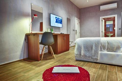 a bedroom with a bed and a desk and a red rug at Quaint Boutique Hotel Xewkija in Xewkija