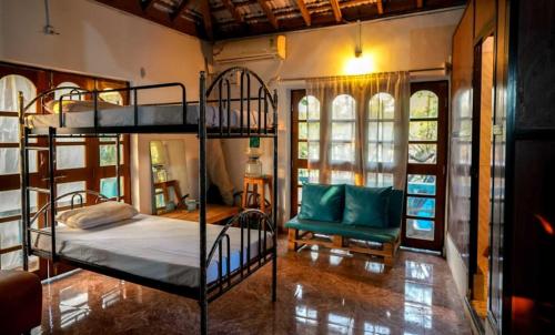 a bedroom with two bunk beds and a chair at Anjoned Hostel & Cafe in Anjuna