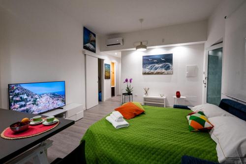 a bedroom with a green bed and a flat screen tv at Domus Enea in Taormina