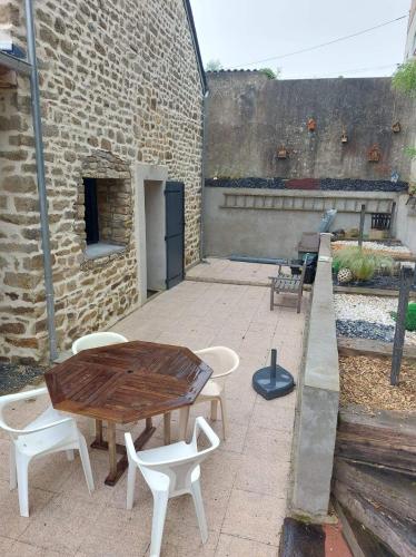 洛里昂的住宿－Studio idéalement situé au calme，一座带木桌和椅子的庭院和一座砖砌建筑