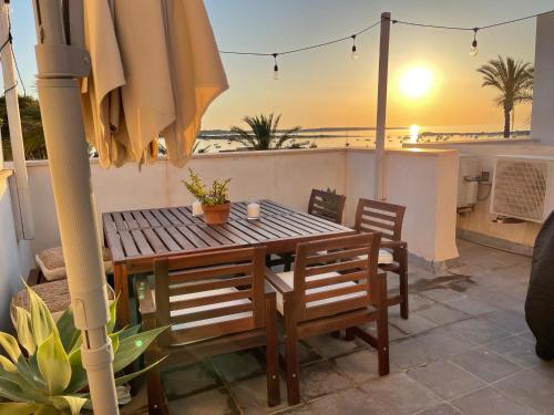 una mesa y sillas con una sombrilla en el balcón en Ponent Formentera en La Savina