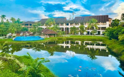 a house with a pool in front of a body of water at Plumeria Lake Resort & SPA in Shertallai