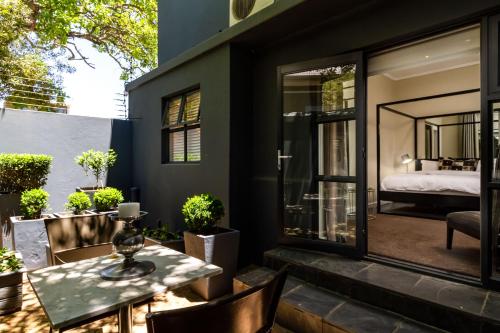 a patio with a table and chairs and a bedroom at Life & Leisure Boutique Guesthouse in Stellenbosch