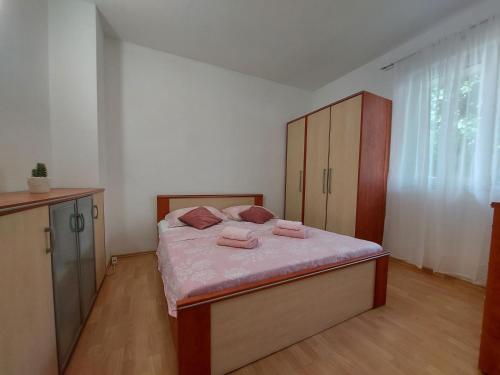 Schlafzimmer mit einem Bett mit rosa Bettwäsche und einem Schrank in der Unterkunft Apartman Nora in Ubli
