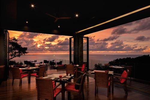 a restaurant with a view of the ocean at sunset at Paresa Resort Phuket in Kamala Beach