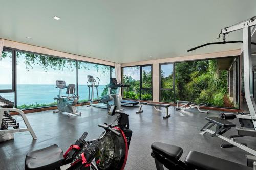 a gym with bikes and exercise equipment and windows at Paresa Resort Phuket in Kamala Beach
