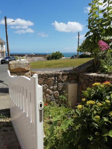 a white fence in a garden with the ocean in the background at L'Échappée Bleue, vue mer in Binic