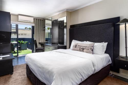 a bedroom with a large white bed and a balcony at Life & Leisure Boutique Guesthouse in Stellenbosch