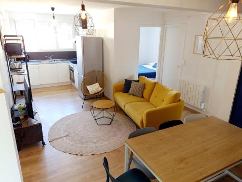 un salon avec un canapé jaune et une table dans l'établissement Le Havre Superbe appartement avec grande terrasse, au Havre