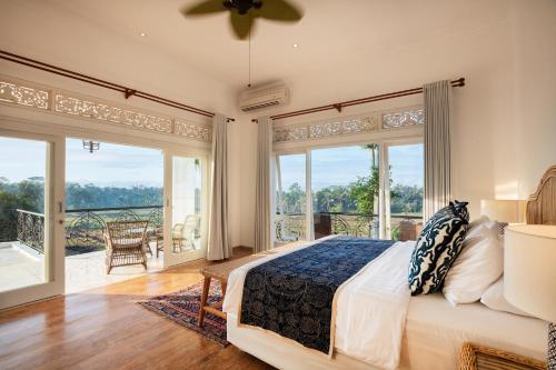 une chambre avec un lit et de grandes fenêtres dans l'établissement Villa Tau, à Tegalalang