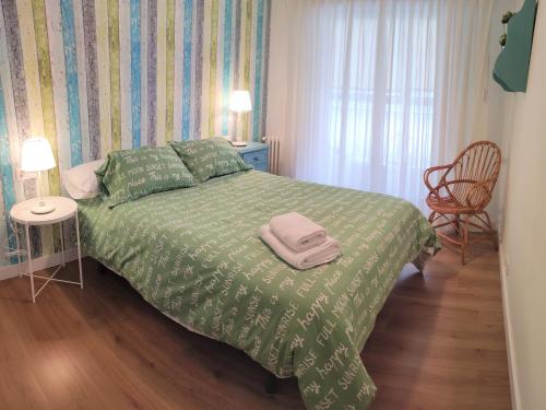 a bedroom with a bed with a green comforter at CARMELA in Santiago de Compostela