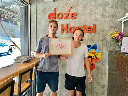 two men holding a sign that says rave hotel at Doze Hostel in Chiang Mai