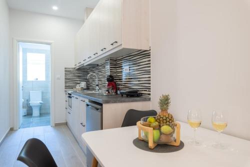 a kitchen with a table with a pineapple and wine glasses at Virvilis Apartments in Sivota