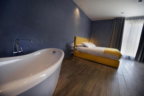 a bathroom with a tub and a bed in a room at Quaint Boutique Hotel Xewkija in Xewkija