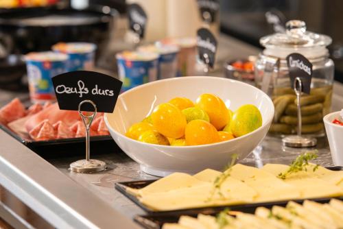 a bowl of fruit on a counter with cheese at Mercure Geneva Airport in Geneva