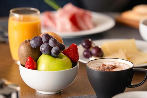 a bowl of fruit on a table with a cup of coffee at Mercure Geneva Airport in Geneva