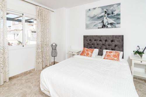 ein weißes Schlafzimmer mit einem großen Bett mit orangefarbenen Kissen in der Unterkunft Spectacular 2 bedroom Penthouse in best location in Nueva Andalucia in Marbella