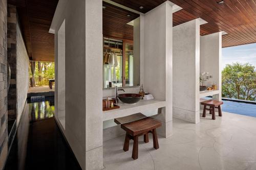 a bathroom with a sink and a counter with a bench at Paresa Resort Phuket in Kamala Beach