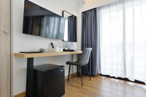 a room with a desk with a television and a chair at Grand BS Airport Hotel Suvarnabhumi in Lat Krabang