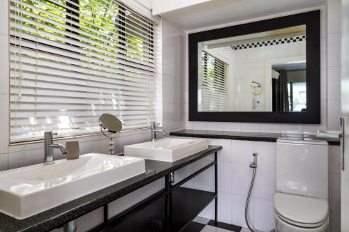 a bathroom with two sinks and a toilet and a mirror at Life & Leisure Boutique Guesthouse in Stellenbosch