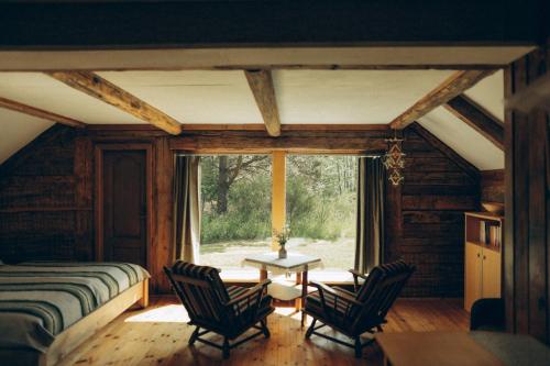 a bedroom with a bed and two chairs and a table at Lūķi, Lauku sēta in Jūrkalne