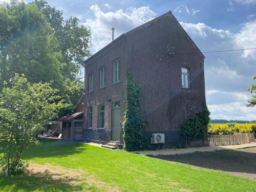 a brick house with a green yard in front of it at Huisje aan de Schelde in Spiere