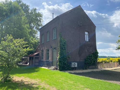 une maison en briques avec une cour verdoyante devant elle dans l'établissement Huisje aan de Schelde, à Spiere